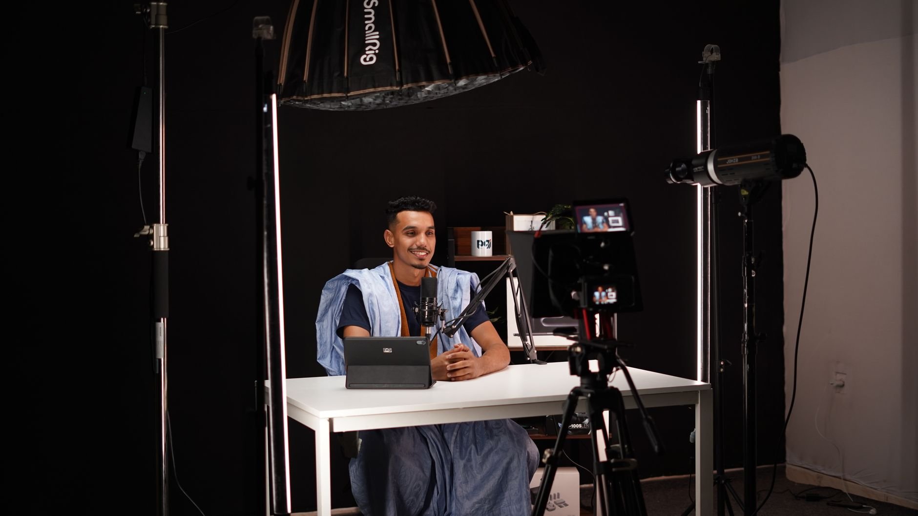 Young man recording a video in a professional studio with lighting and camera equipment.